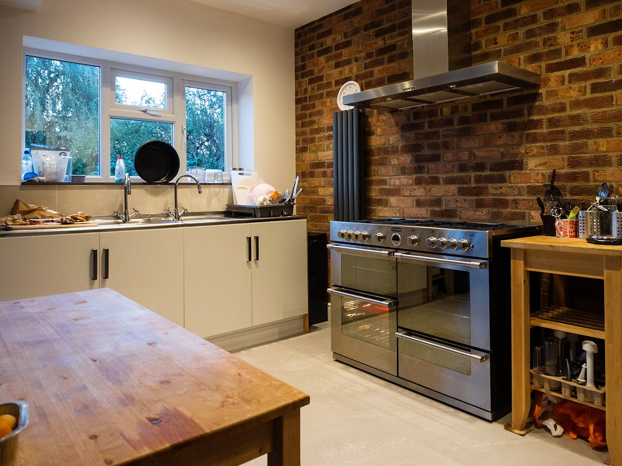 Charming kitchen featuring rustic brick wall, stainless steel range, and cozy interior setting.